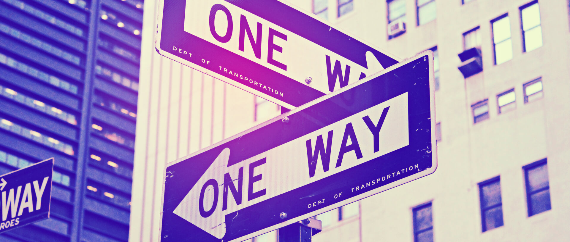 Close-up of two one-way road signs pointing in opposite directions.